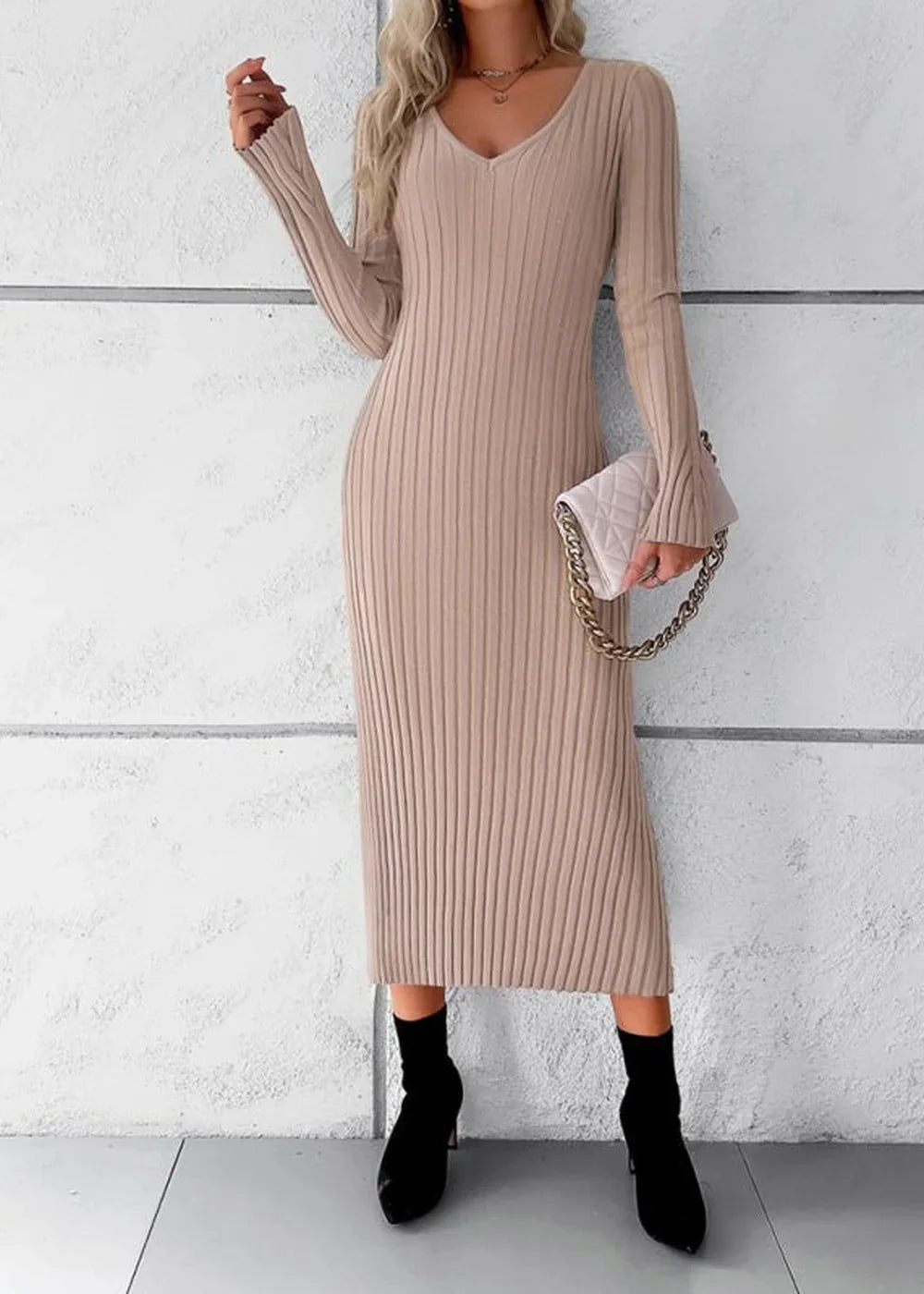 Khaki ribbed knit midi sweater dress with v-neck and bell sleeves, held with a quilted handbag.