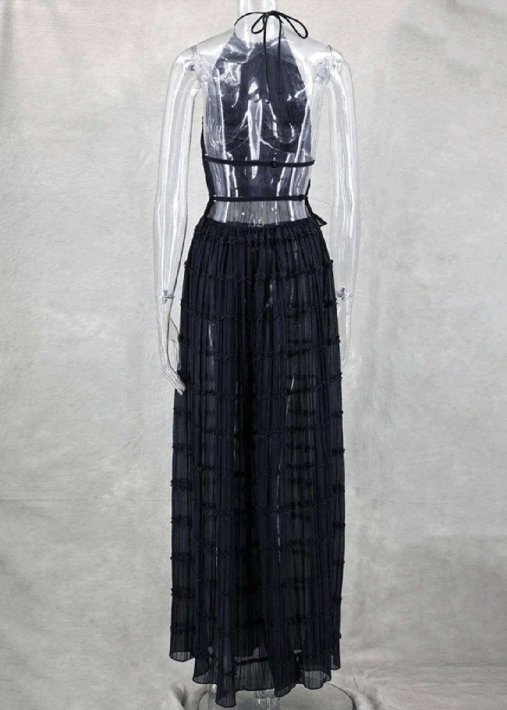 Black pleated maxi dress with halter neck and sheer back detail on a mannequin.