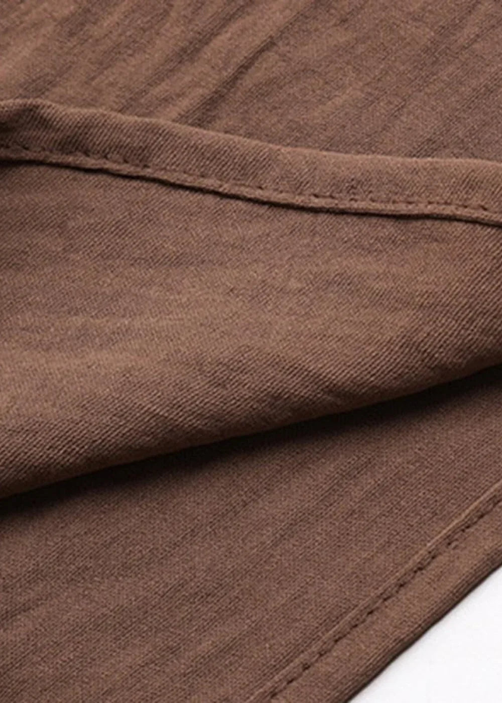 Close-up of brown fabric with visible stitching detail and a subtle texture.