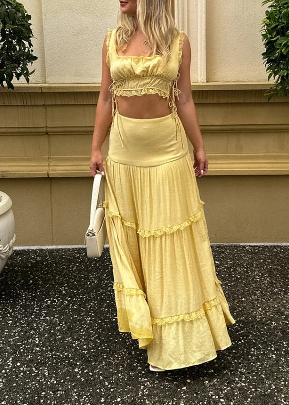 A yellow tiered maxi skirt with ruffled trim, paired with a matching cropped tie-front top.