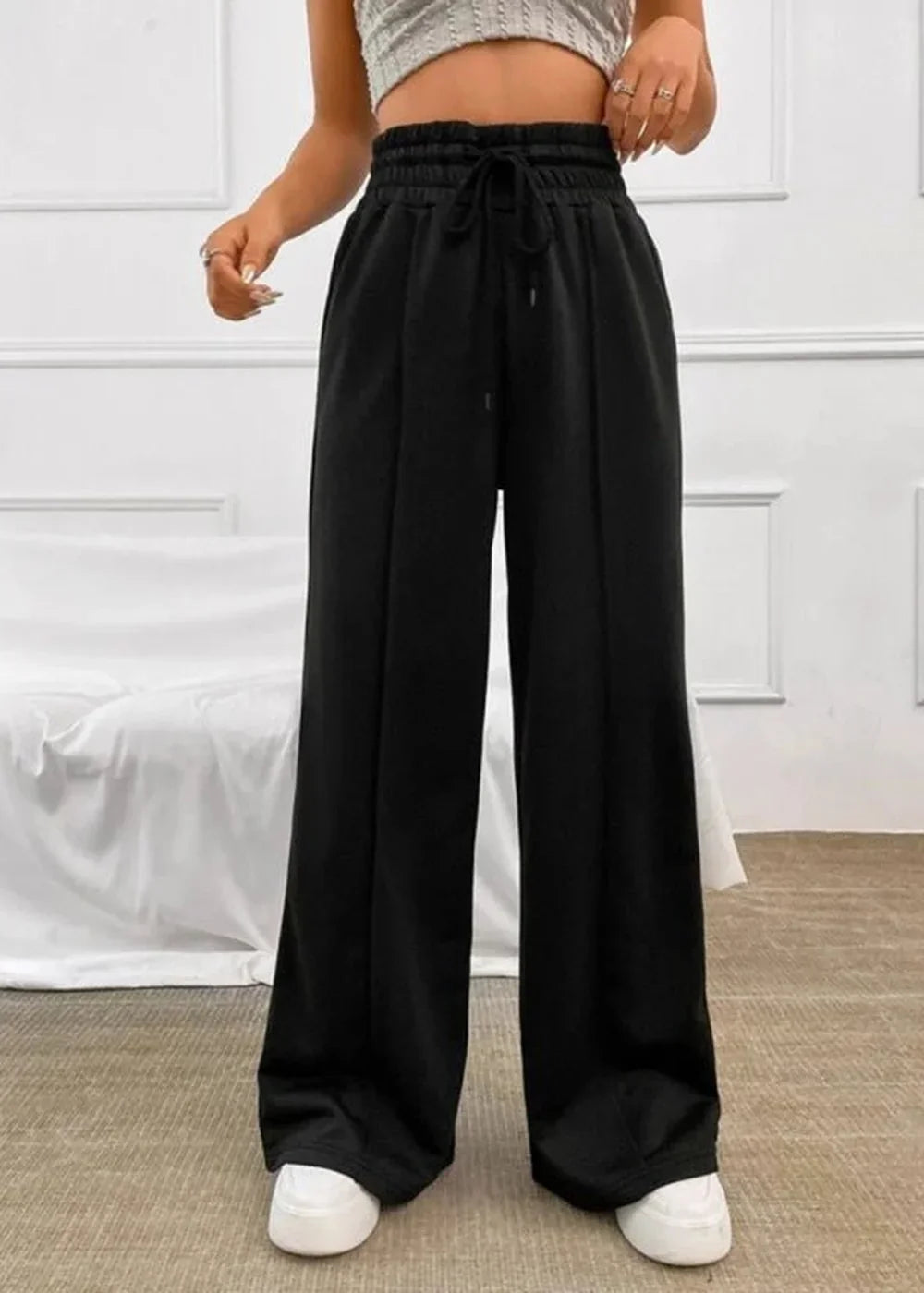 Black wide-leg pants with drawstring waist and vertical seam detail, full length on model.