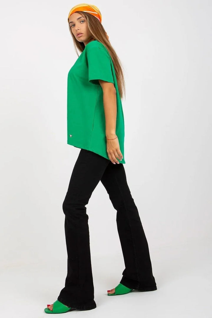 Green oversized t-shirt with black flared pants and bright green slides on a model.