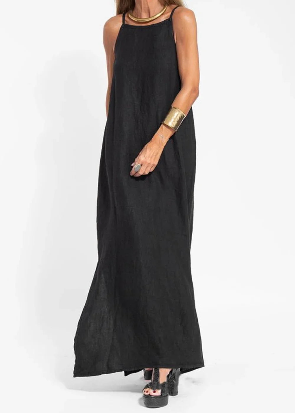 Black maxi dress with a flowy silhouette, gold necklace, and statement cuff bracelet on model.