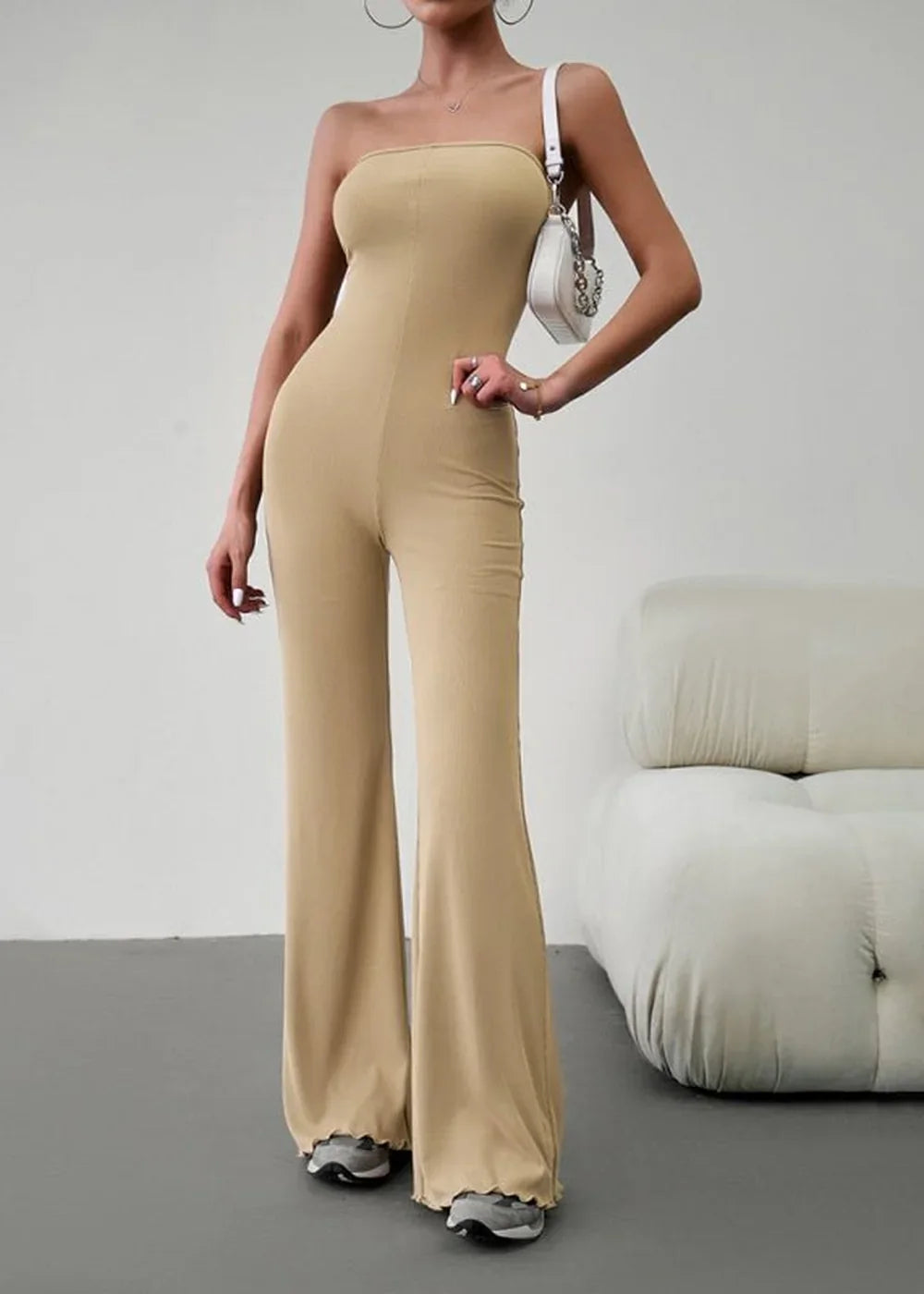 Khaki strapless wide-leg jumpsuit with a ribbed texture and lettuce hem, worn by a model with a white shoulder bag.