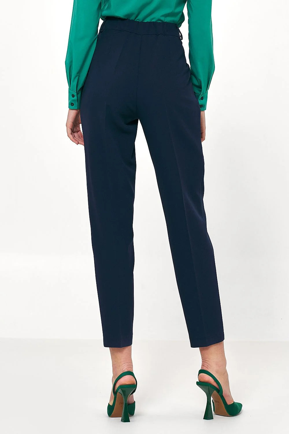 Navy blue tapered trousers with a high waist and green slingback heels.