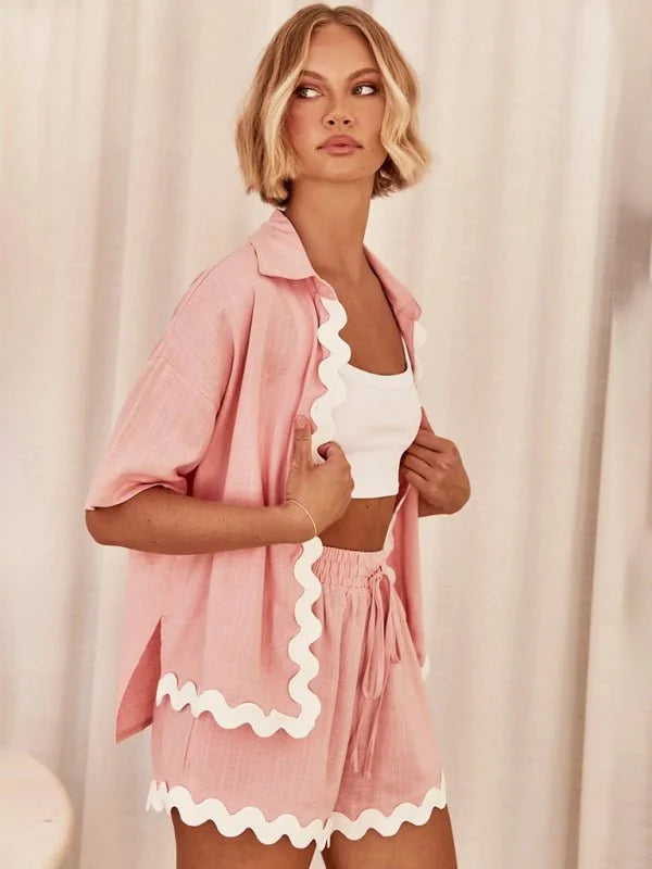 Pink linen-blend shorts suit with scalloped white trim, drawstring waist, and matching open shirt.