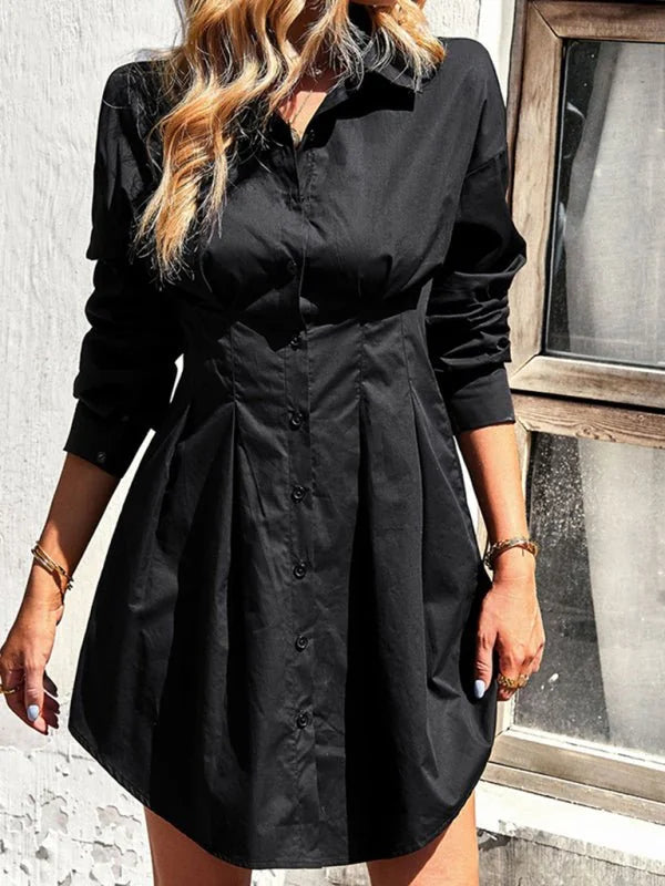 Black cotton shirt dress with button front, pleated skirt, and gold bracelets on model.