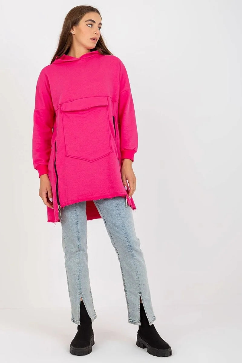Bright pink tunic hoodie with side zippers and front pocket, worn with light wash jeans and black boots.