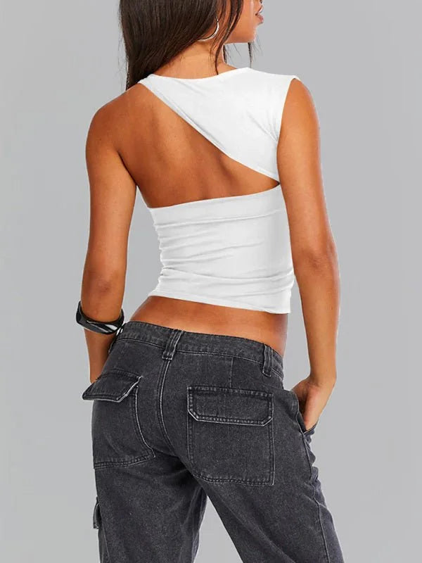 White one-shoulder crop top with cut-out detail, paired with dark wash cargo pants.