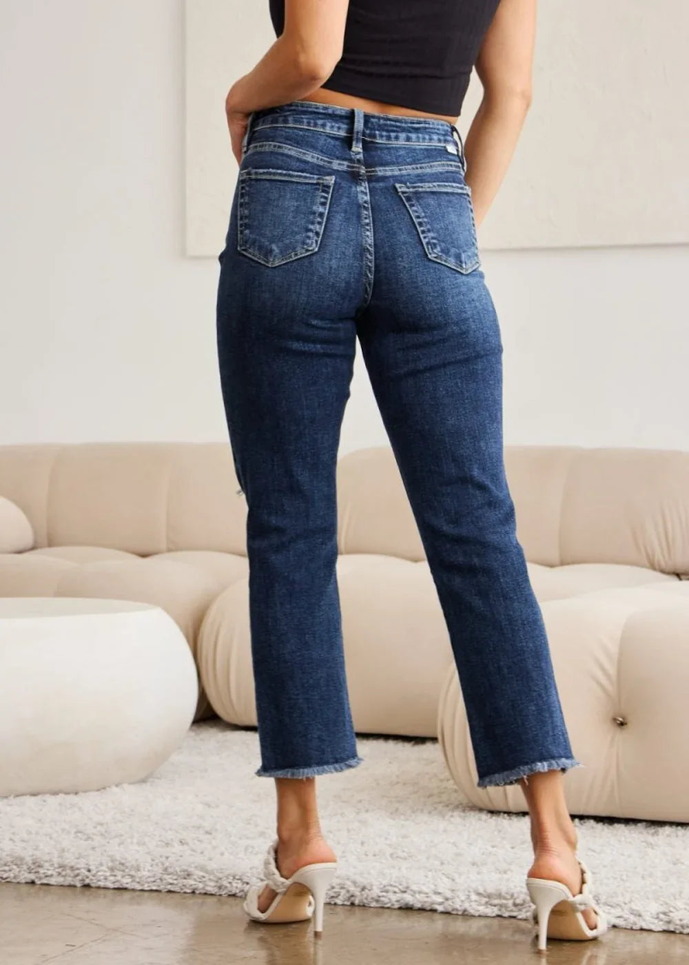 Dark wash denim jeans with frayed hems and a regular fit shown from the back.