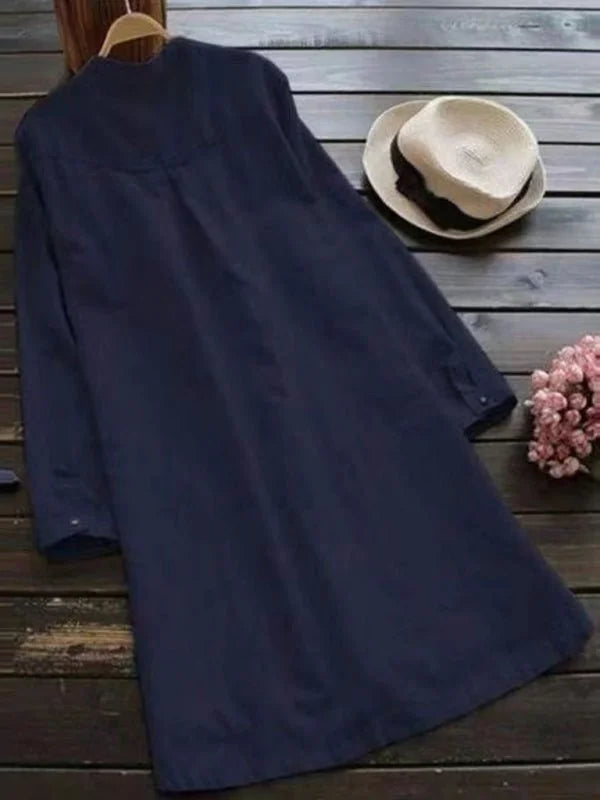Navy blue long-sleeved tunic with button details, styled with a straw hat.