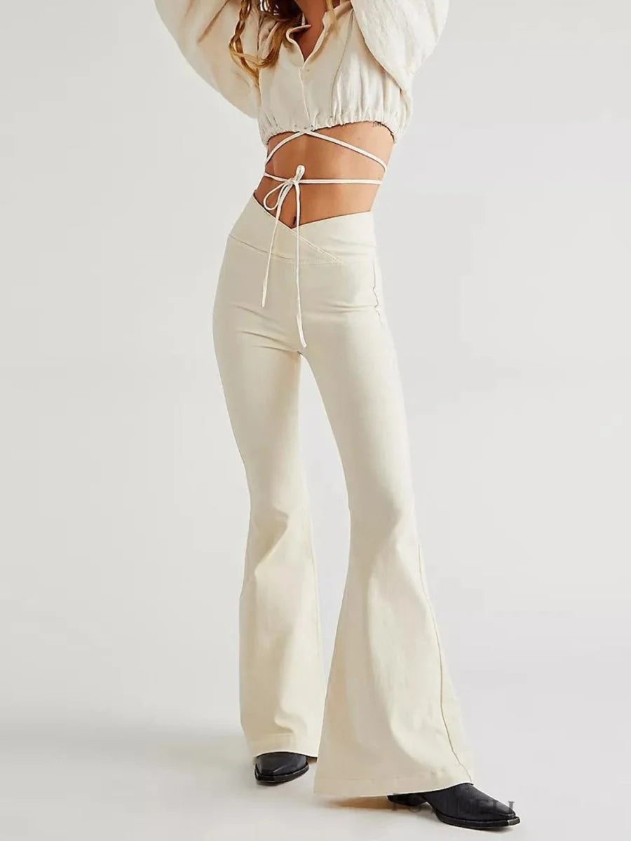 Cream high-waisted flare pants with a v-shaped front detail and tie-front crop top on model.