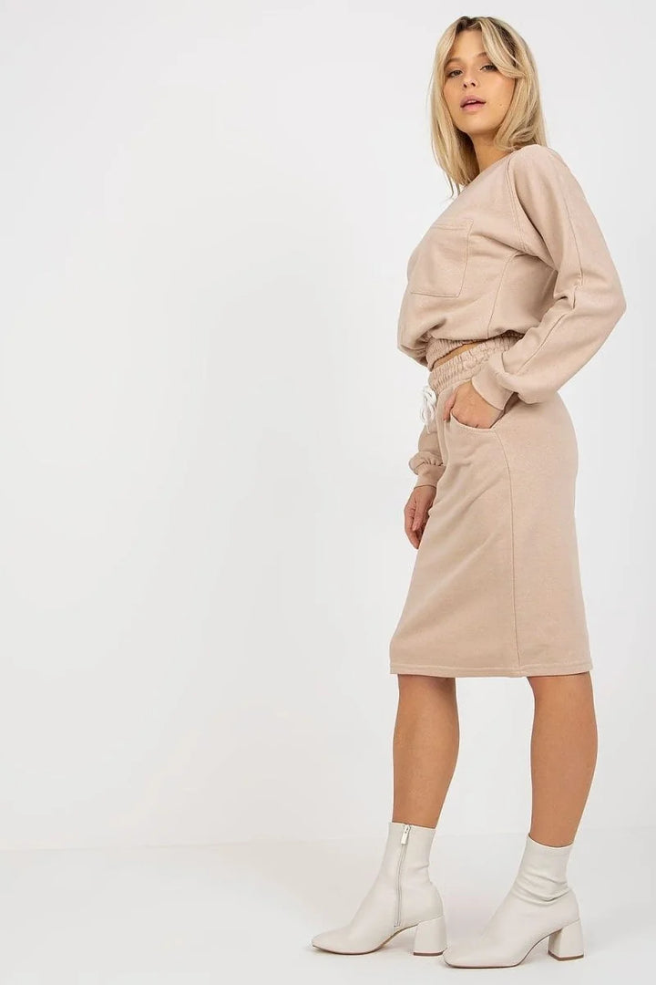 Light beige cotton-blend sweat suit with a cropped top and midi skirt, worn with white boots.