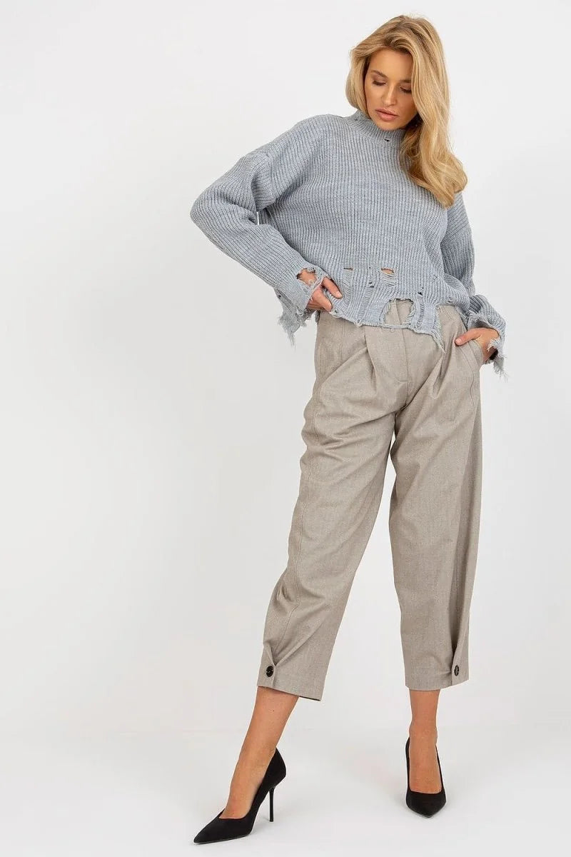 Light gray distressed knit sweater with a mock neck, paired with loose tan capri pants and black heels.