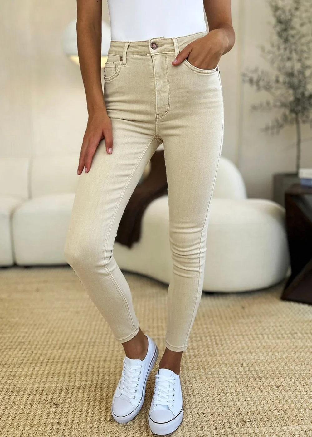 Cream cotton blend skinny jeans with a regular fit, worn by a model with white sneakers.