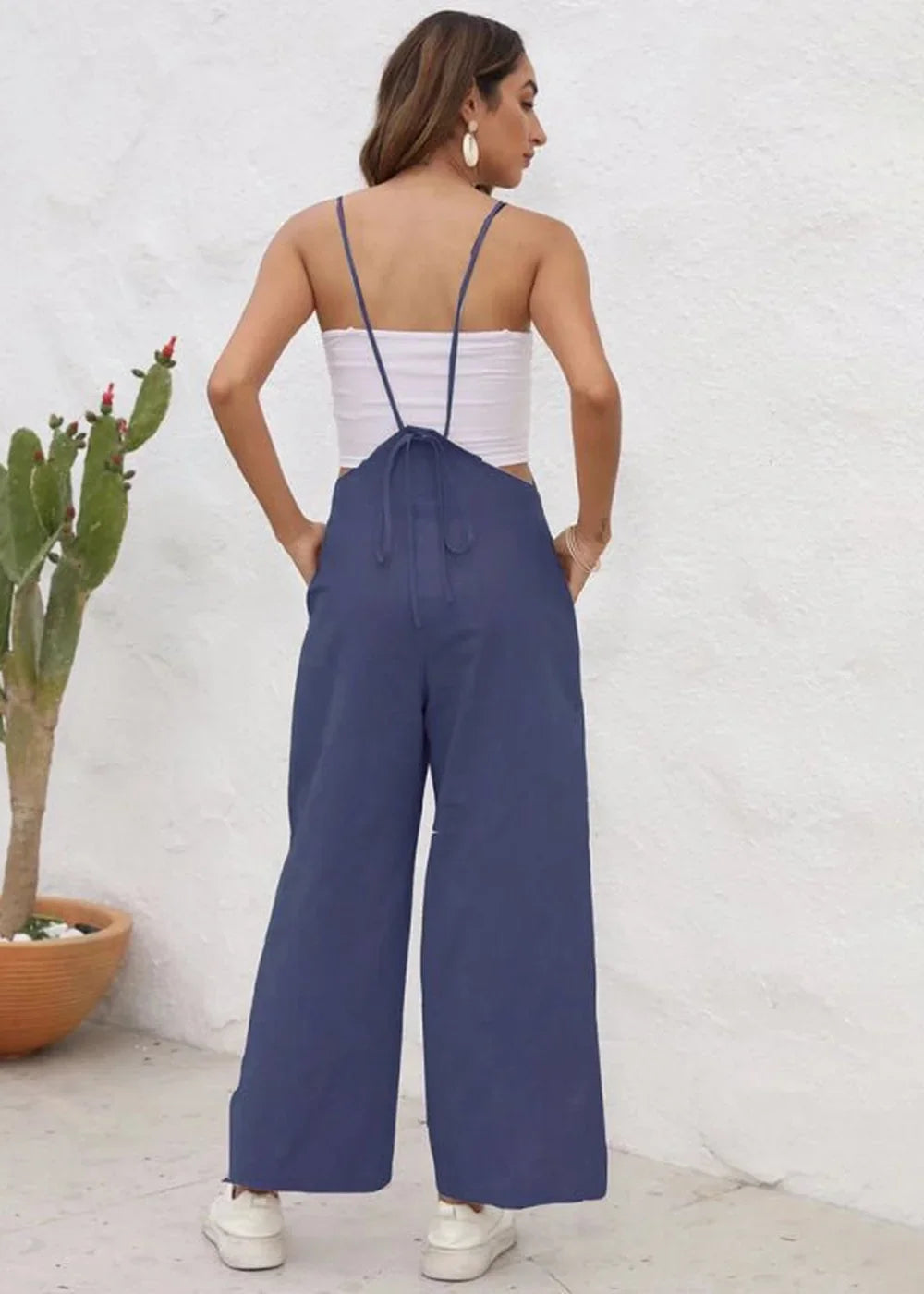 Navy blue wide-leg jumpsuit with spaghetti straps and tie-back detail, on a model.