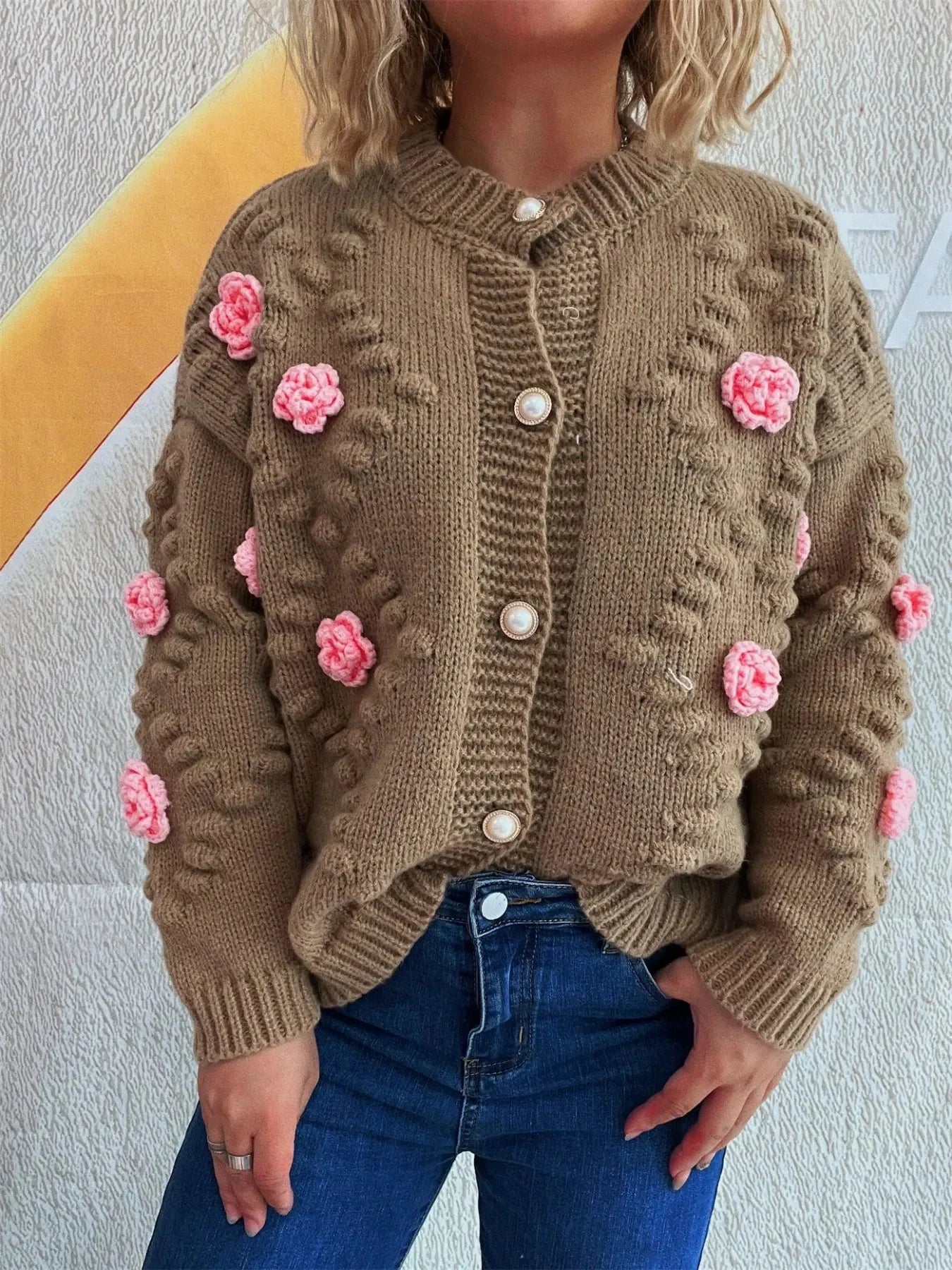 Brown knit cardigan with pink floral appliques and pearl buttons.