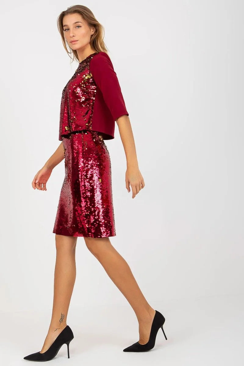 Woman in a sparkly red sequin dress and matching bolero, black heels.