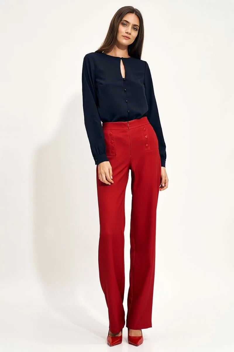 High-rise red wide-leg pants with button details and a tucked-in navy blue blouse on a model.