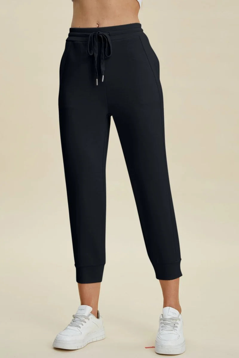 Black joggers with a drawstring waist and cuffed ankles, shown on a model.