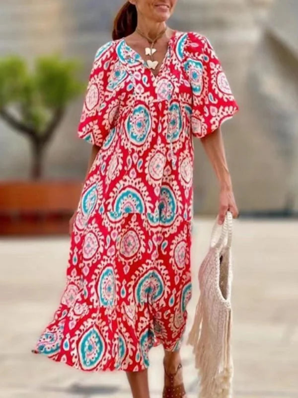 Red bohemian maxi dress with geometric pattern, V-neck, and fringe tote bag.
