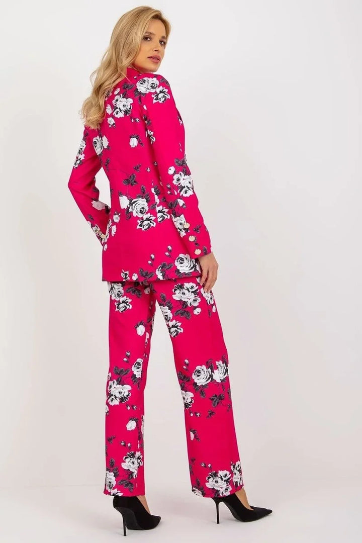 Bright pink blazer and pants with a bold black and white floral print, on a woman wearing black heels.