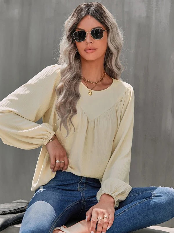 Cream peasant blouse with gathered neckline and balloon sleeves, worn by a model with sunglasses.