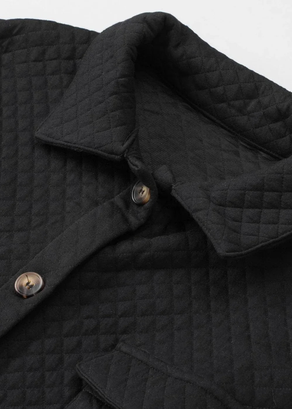 Close-up of a black quilted jacket with diamond pattern and brown button details.