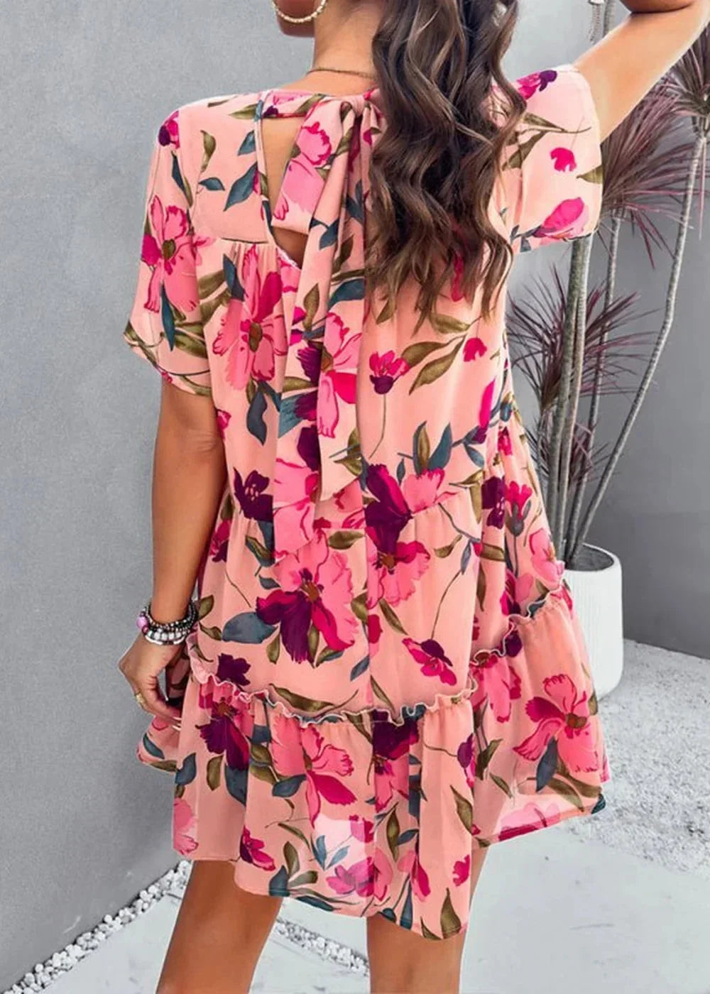 Pink floral print chiffon dress with tiered ruffles and a tie-back detail.