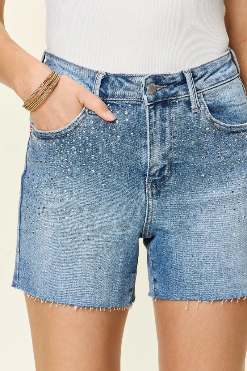 Light wash denim shorts with a high waist and frayed hem, embellished with scattered rhinestones.