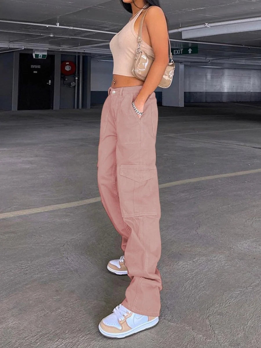 Pink cargo pants with large side pockets on model with white and tan sneakers.