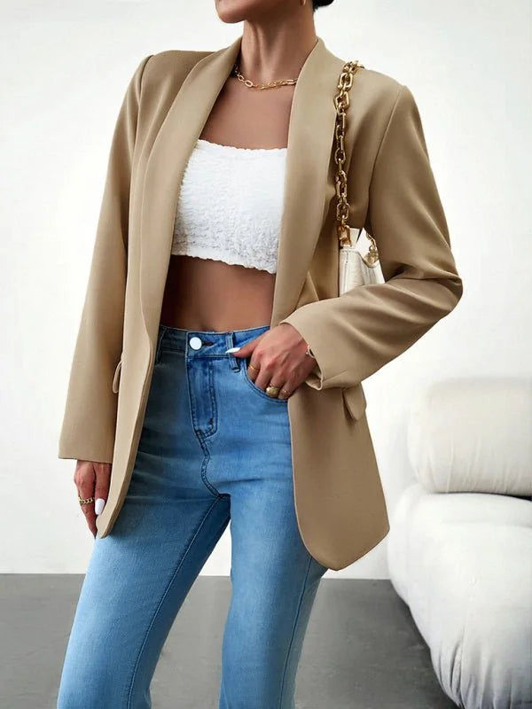 Tan blazer with a white textured crop top, light wash denim jeans, and gold chain handbag on model.
