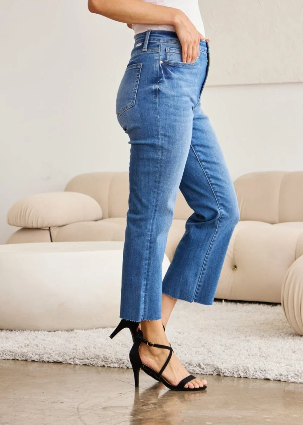 Medium wash denim jeans with a frayed hem and a slim, straight leg fit, shown on a model.