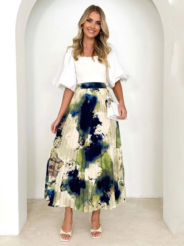 Pleated midi skirt with abstract navy, green, and cream print, on model.