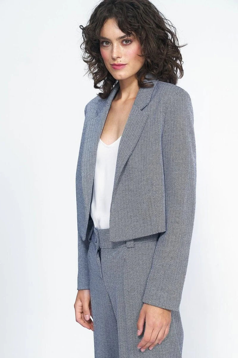 Woman in a navy and white herringbone patterned cropped blazer and matching pants.