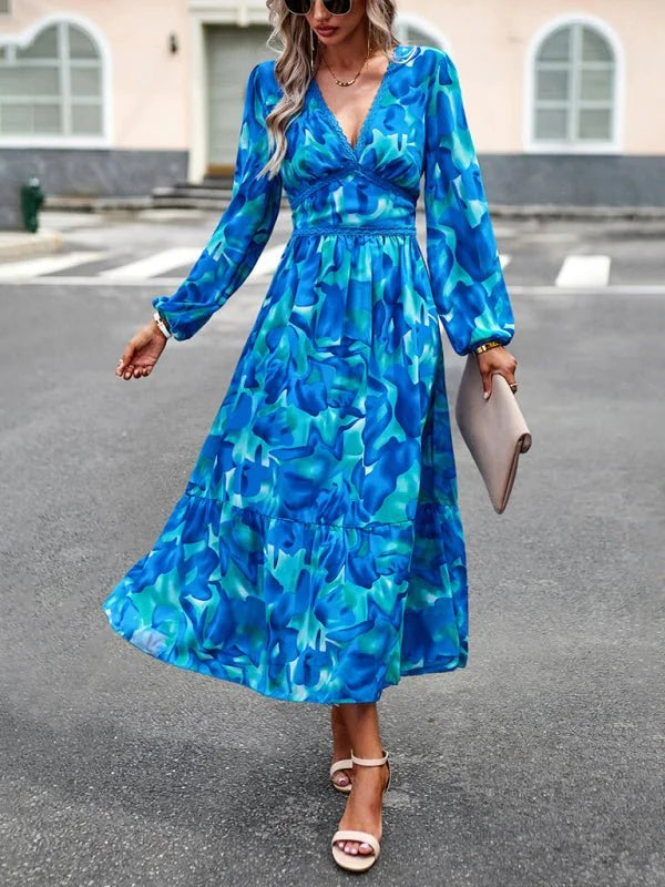 Blue and teal abstract print midi dress with V-neck and long sleeves, on a woman.