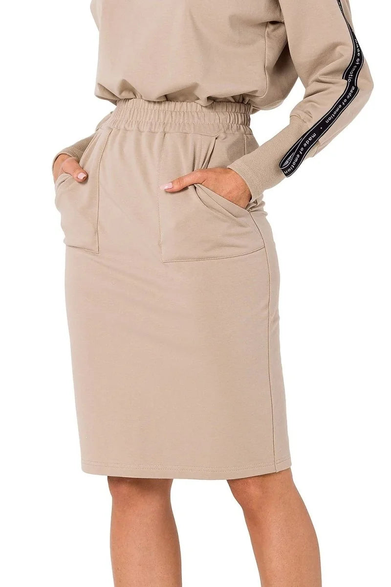 Close-up of a beige cotton-blend skirt with elastic waist and pockets, showing texture.