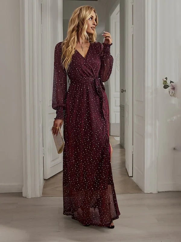 Burgundy long-sleeved maxi dress with white polka dots, v-neck, and tie waist, on model.