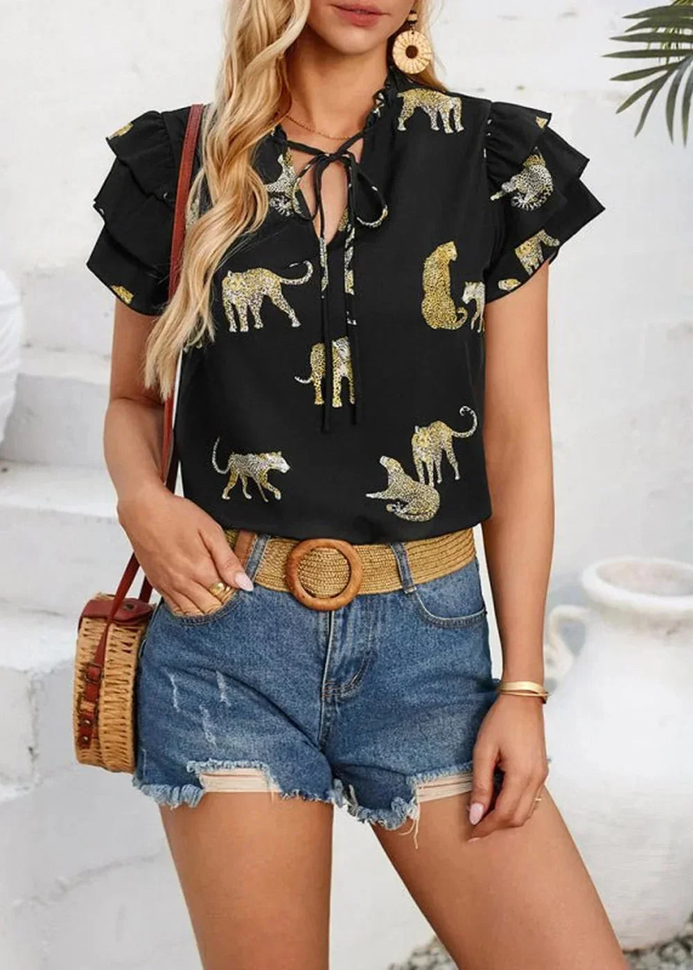 Black short-sleeve top with gold leopard print, tie-neck, and ruffled sleeves on a model.