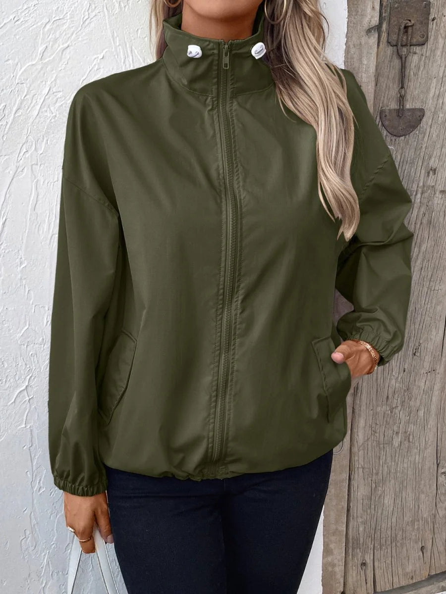 Olive green lightweight jacket with a high collar, full zipper, and cinched cuffs, shown on a model.