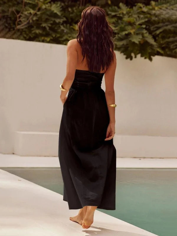 Black strapless maxi dress with gold bracelets on model, showing back view.