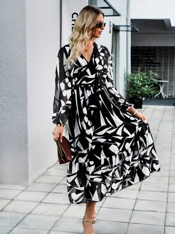 Black and white abstract print maxi dress with long sleeves, v-neck, and tiered skirt, worn by a model.
