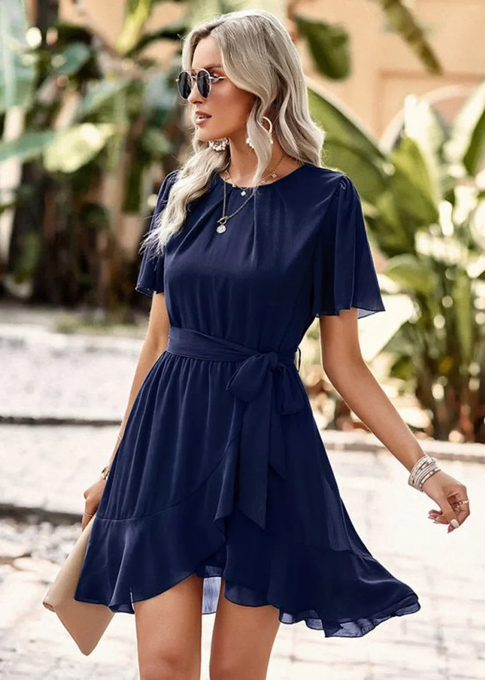 Navy blue ruffled wrap dress with flutter sleeves and a tie waist, worn by a model outdoors.