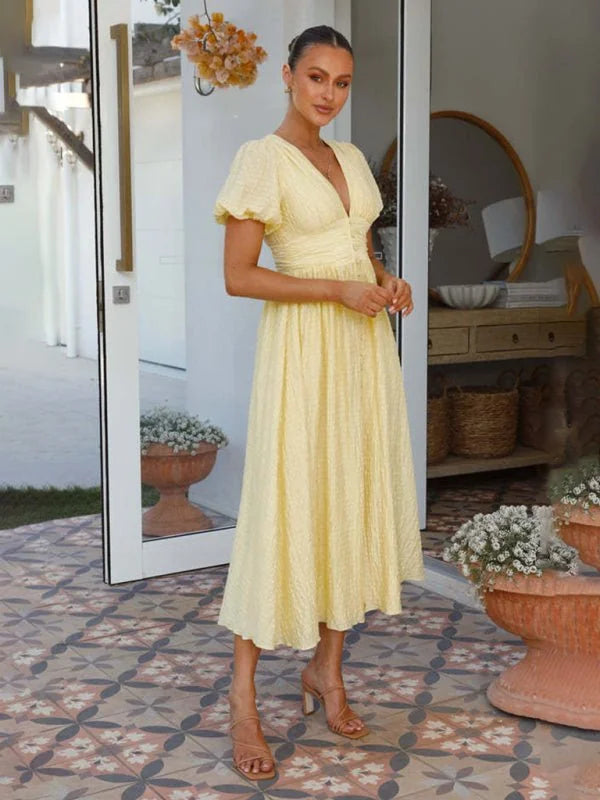 Light yellow textured midi dress with short puff sleeves and a V-neck on a model.