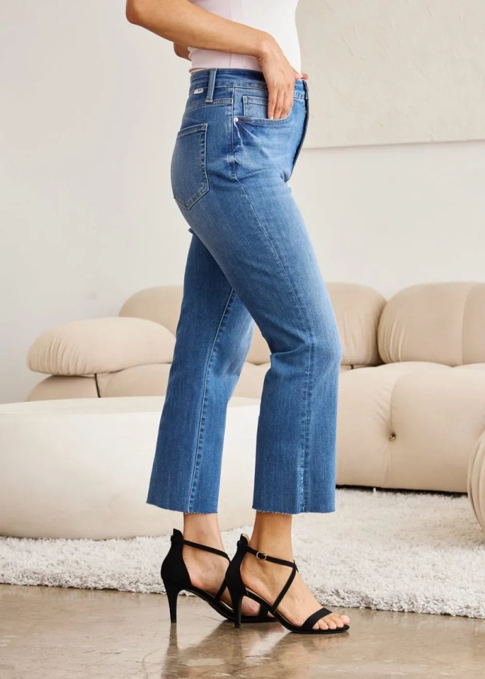 Blue denim jeans with a frayed hem, worn with black heeled sandals.