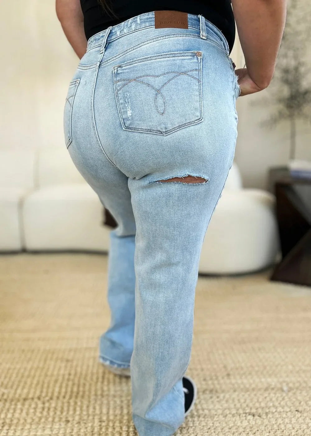 Light wash denim jeans with a distressed detail and a ripped section on the thigh.