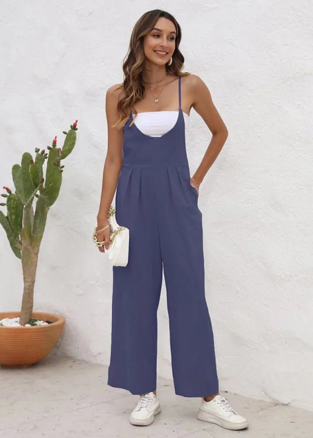 Navy blue wide-leg jumpsuit with white top and white sneakers on a model.