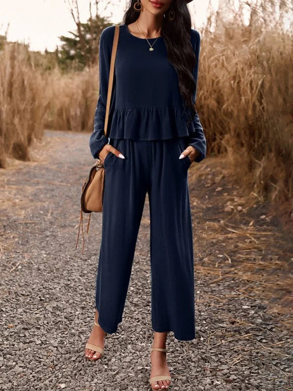 Navy blue ruffled long-sleeve top and wide-leg pants suit with a crossbody bag on model.