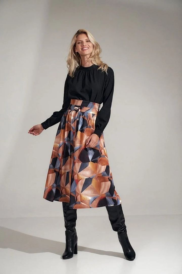 Black blouse with a high neckline, paired with a midi skirt featuring a geometric abstract print in rust, black, and cream.