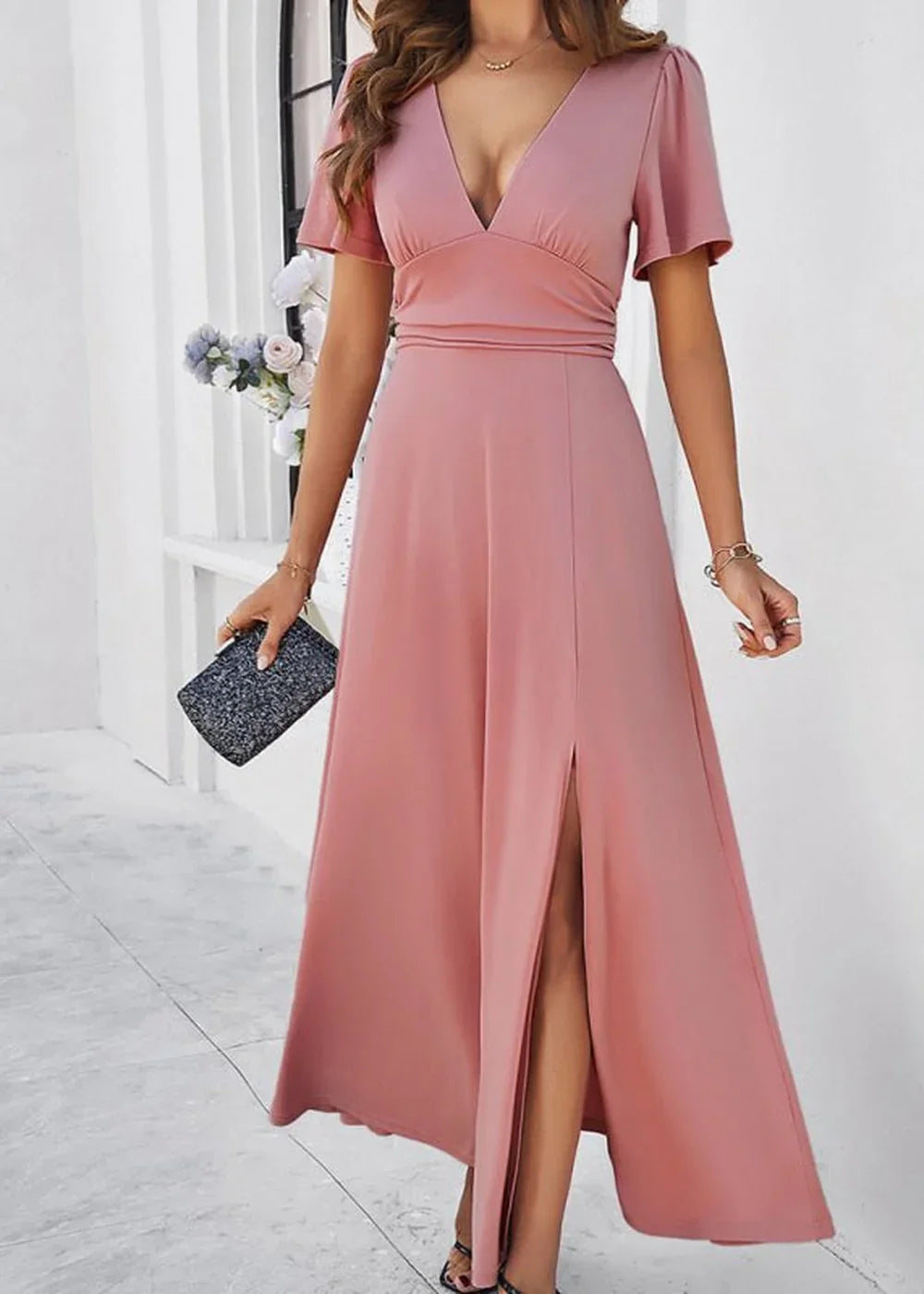 Pink maxi dress with a deep V-neck, flutter sleeves, and a high slit, shown on a model.